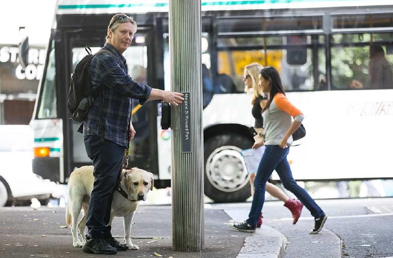 man reading tactile sign at street corner